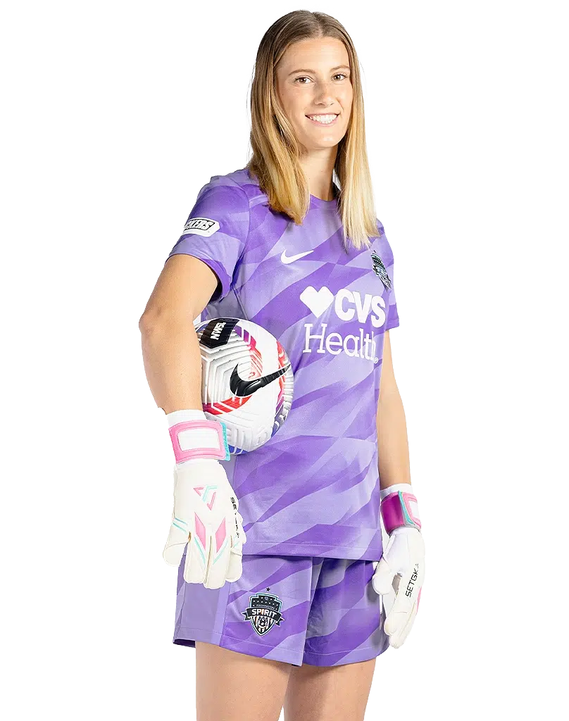 Lyza Bosselmann is turned three-quarters to her left. She is wearing a purple goalie kit and gloves.
