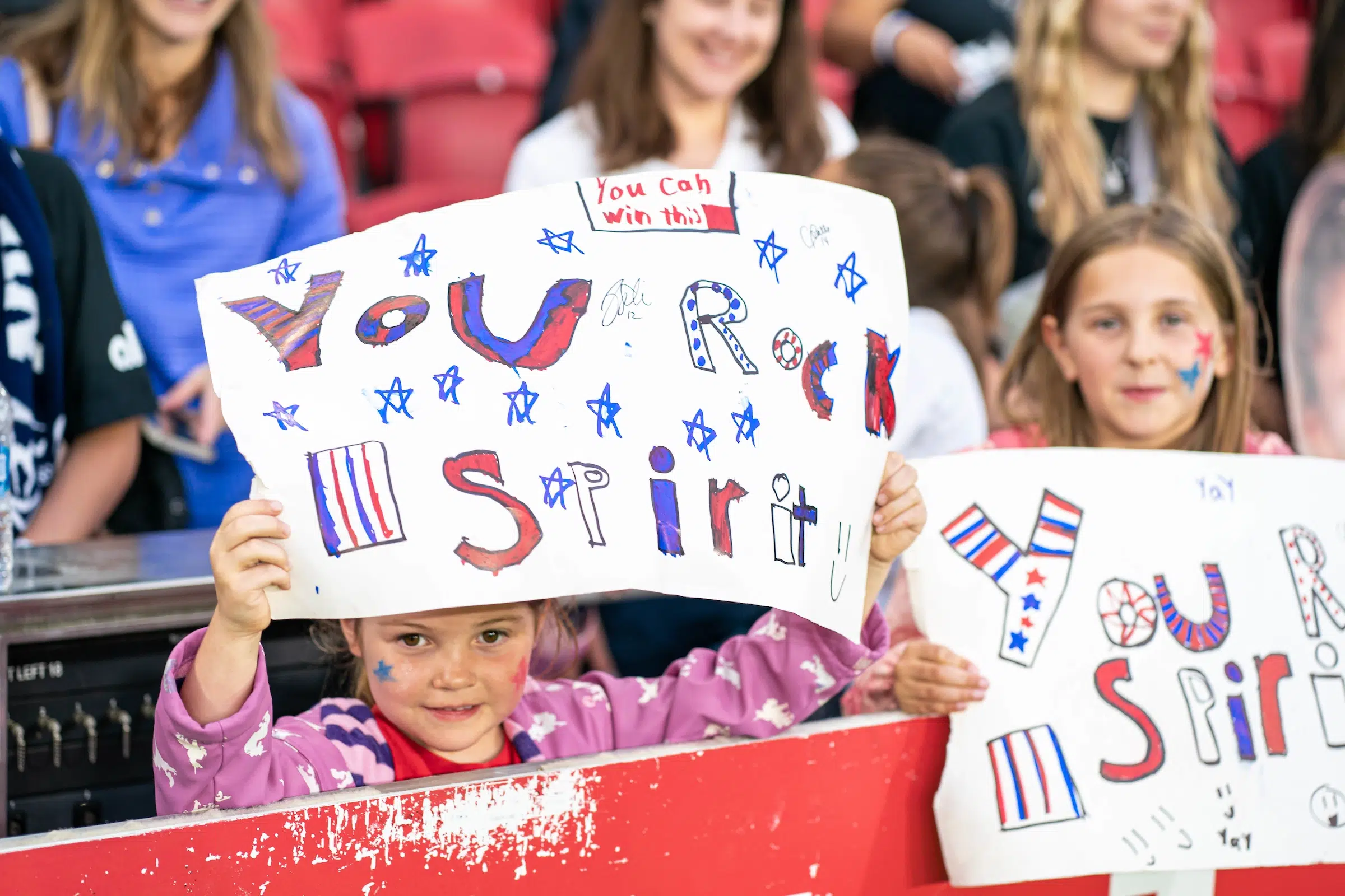 Two young fans hold up handmade signs that read "you rock spirit" in blue and red marker.