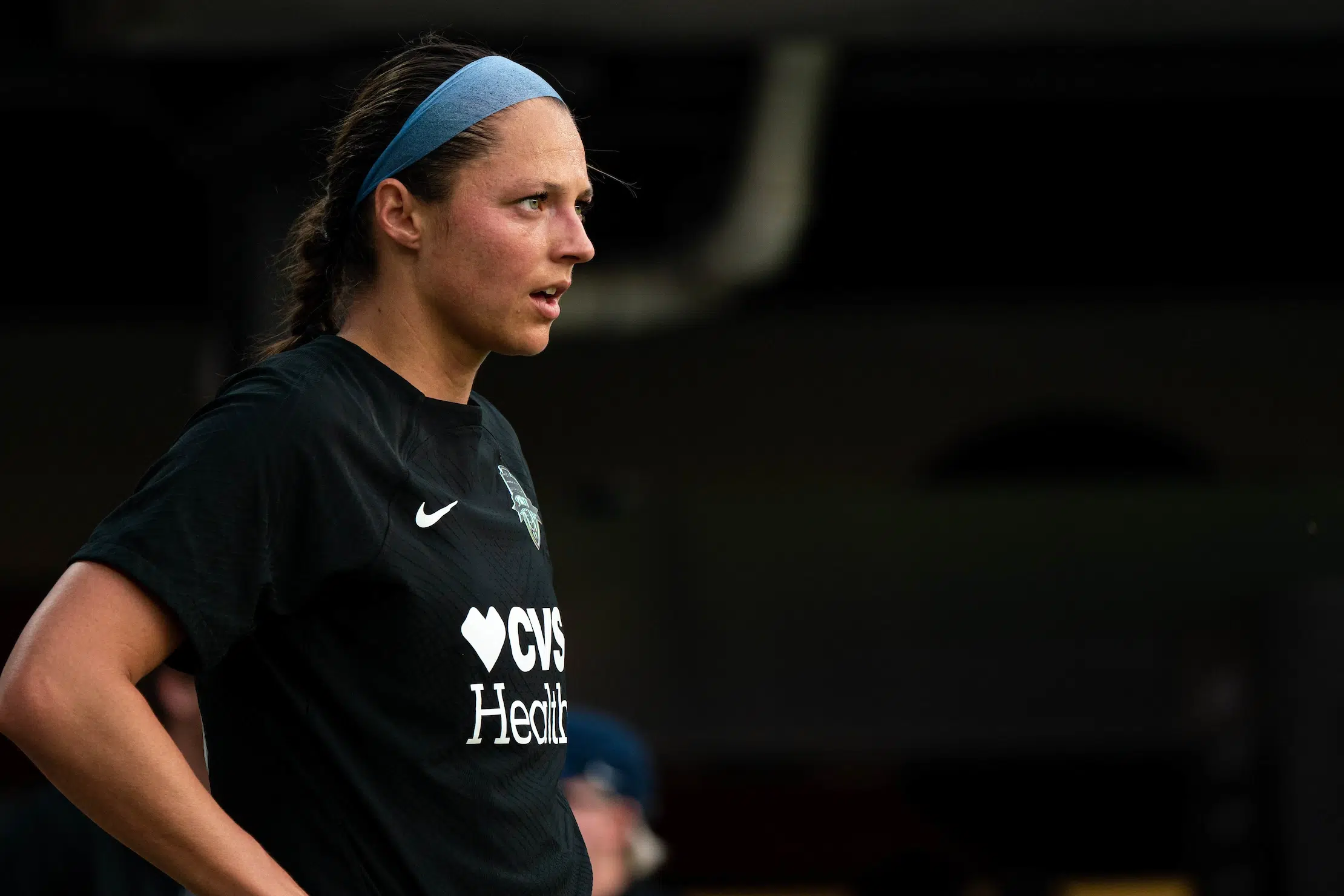 A profile view of Ashley Hatch in a black uniform with her brown hair in a braid.