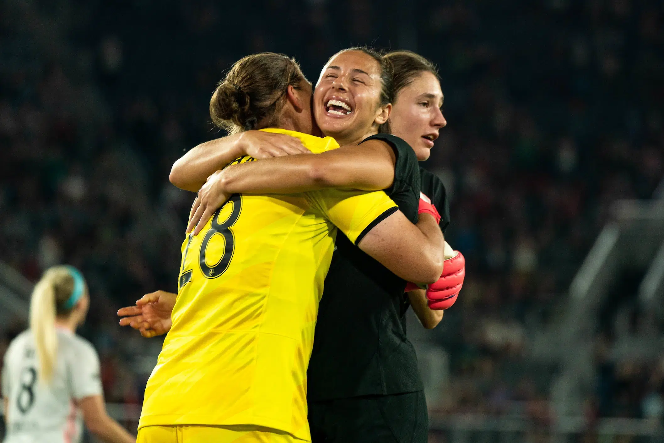 Nicole Barnhart in a yellow jersey and Sam Staab in a black jersey hug and smile.