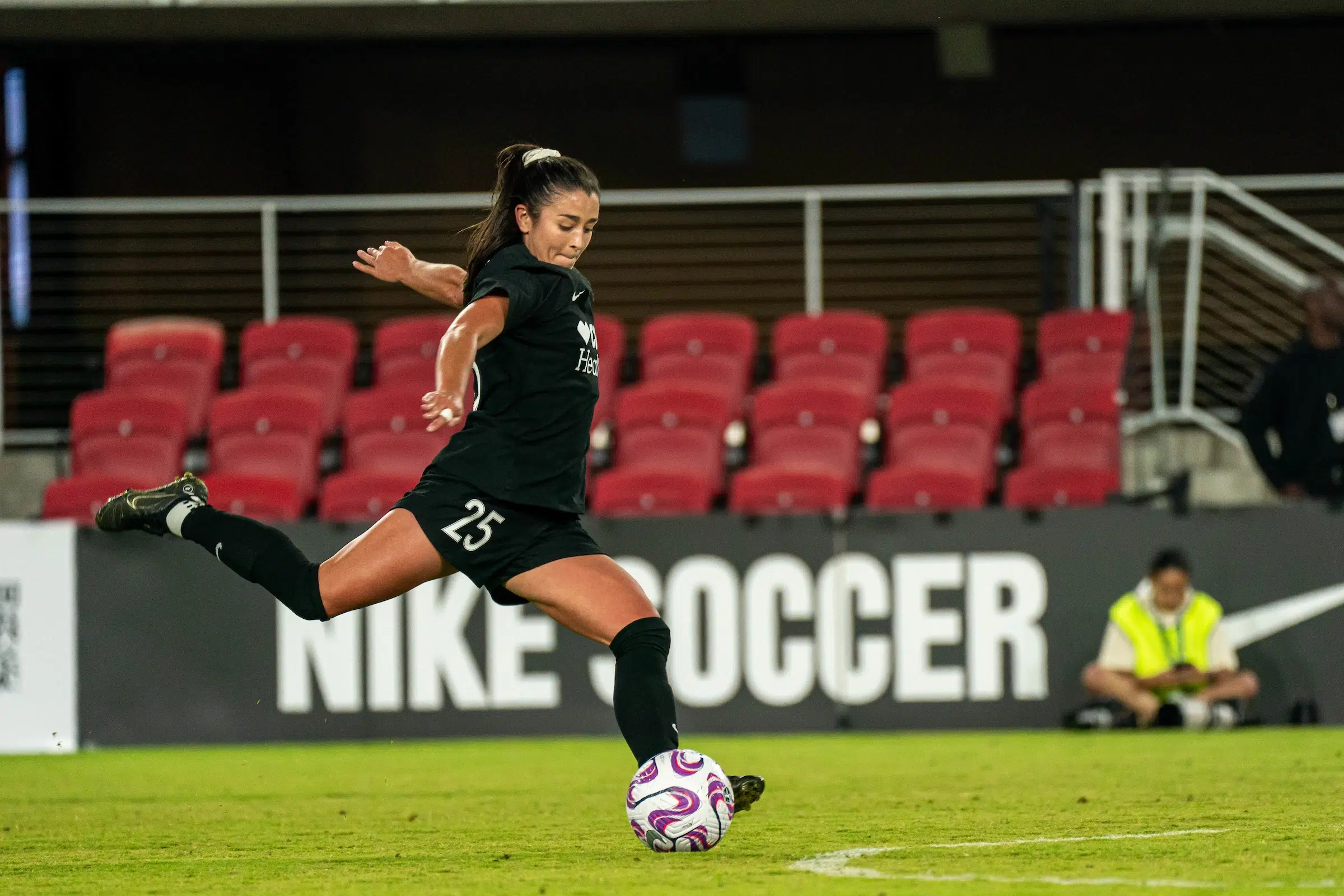 Marissa Sheva in an all black uniform prepares to kick a soccer ball.