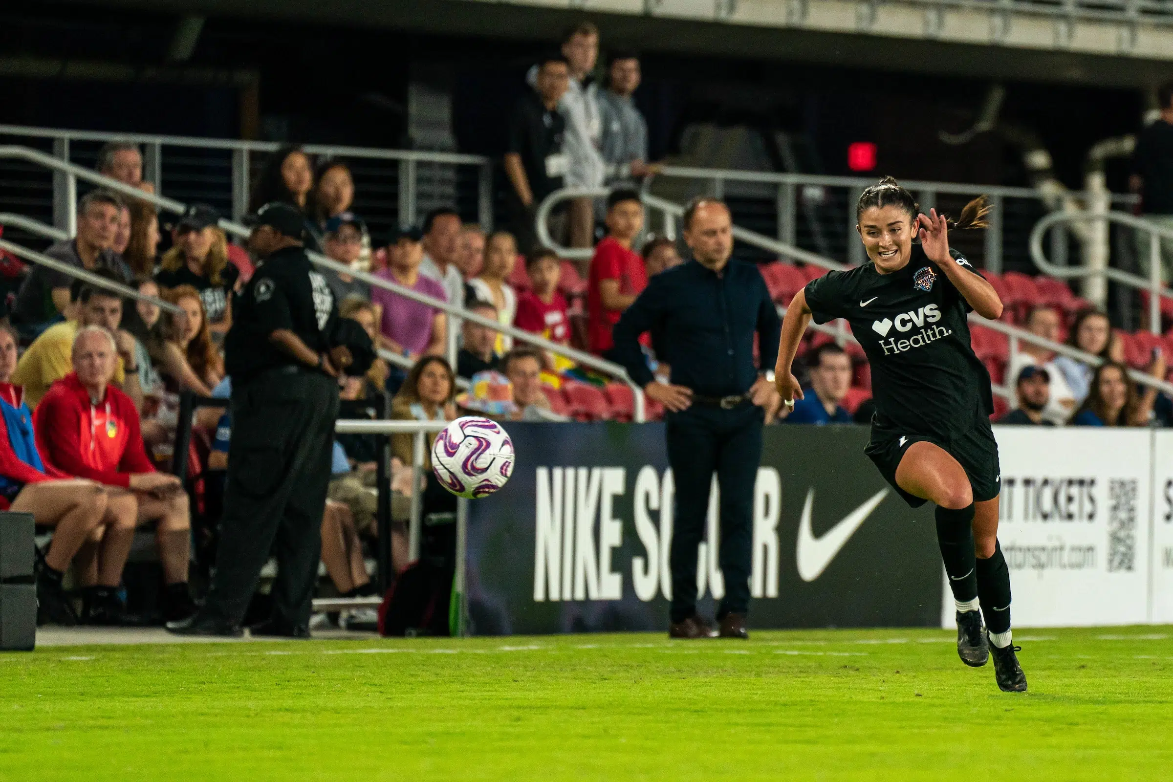 Marissa Sheva in a black uniform chases down a soccer ball.