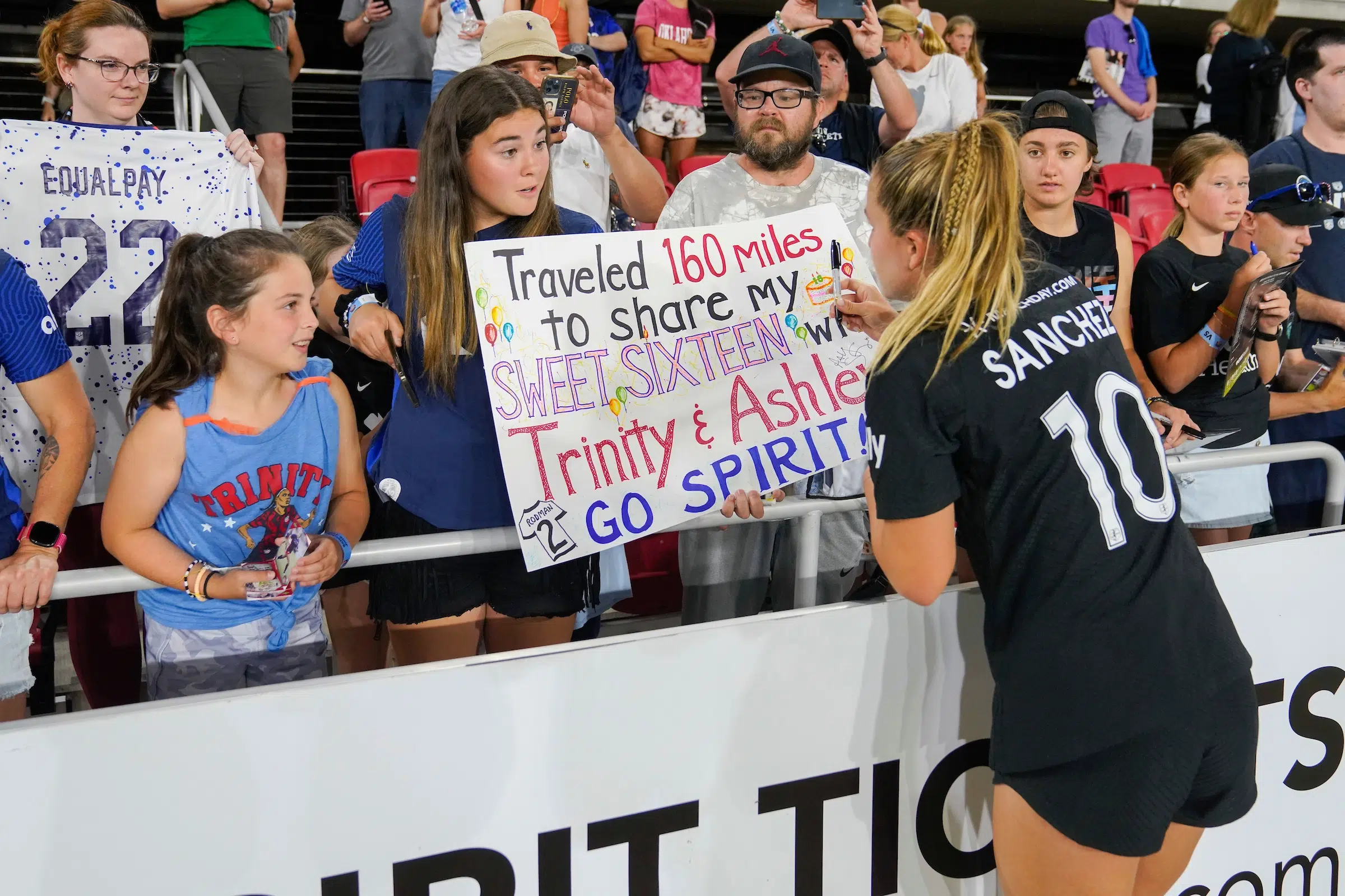Ashley Sanchez signs a poster held by a young fan.