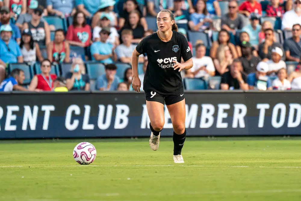 Tara McKeown in a black uniform dribbles a soccer ball.
