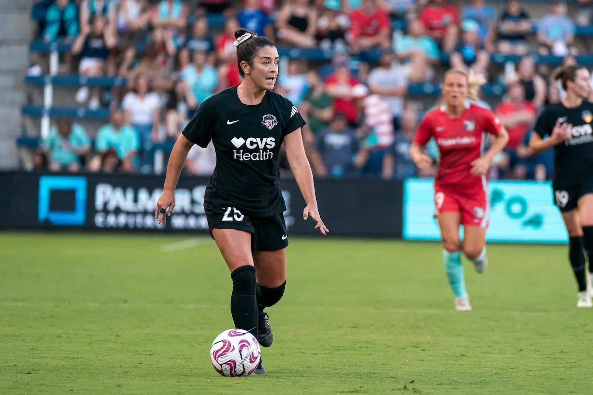 Marissa Sheva in a black uniform dribbles a soccer ball.