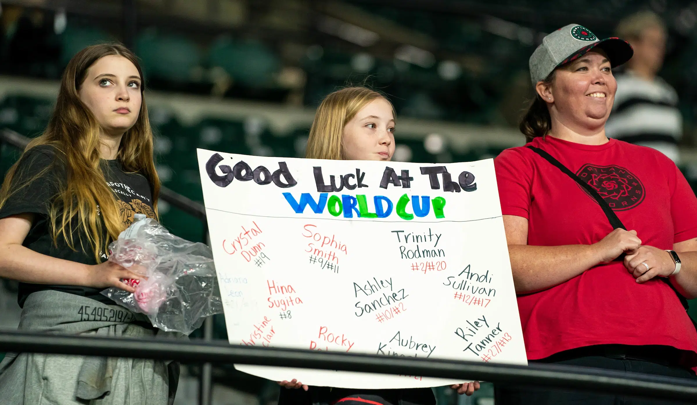 A young fan holds up a handwritten poster that reads "Good luck at the World Cup"