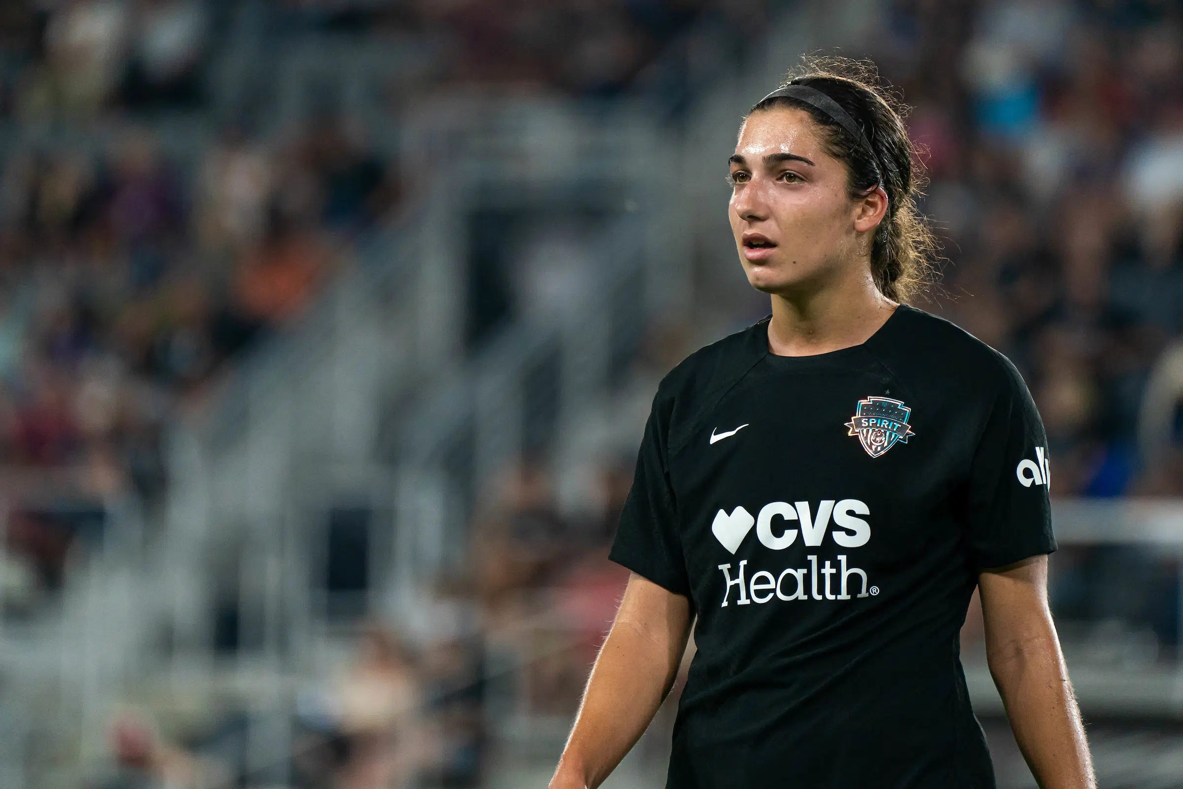 Lena Silano in a black uniform stands on a soccer field.