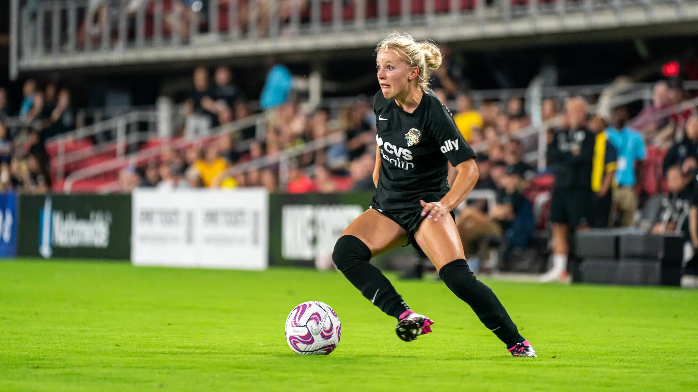 Chloe Ricketts in an all-black uniform dribbles a soccer ball.