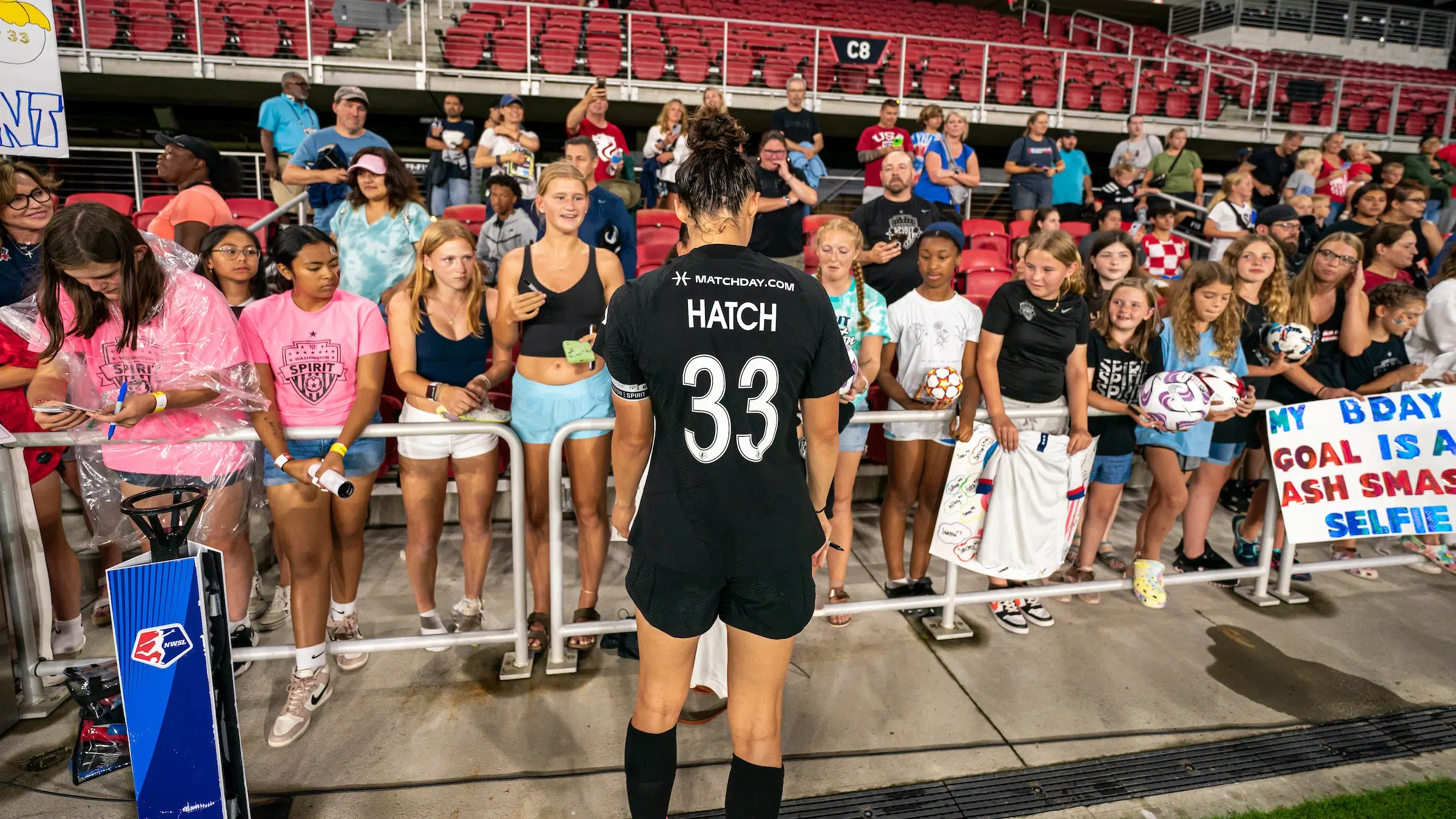 Ashley Hatch in a black uniform interacts with young fans after the game.
