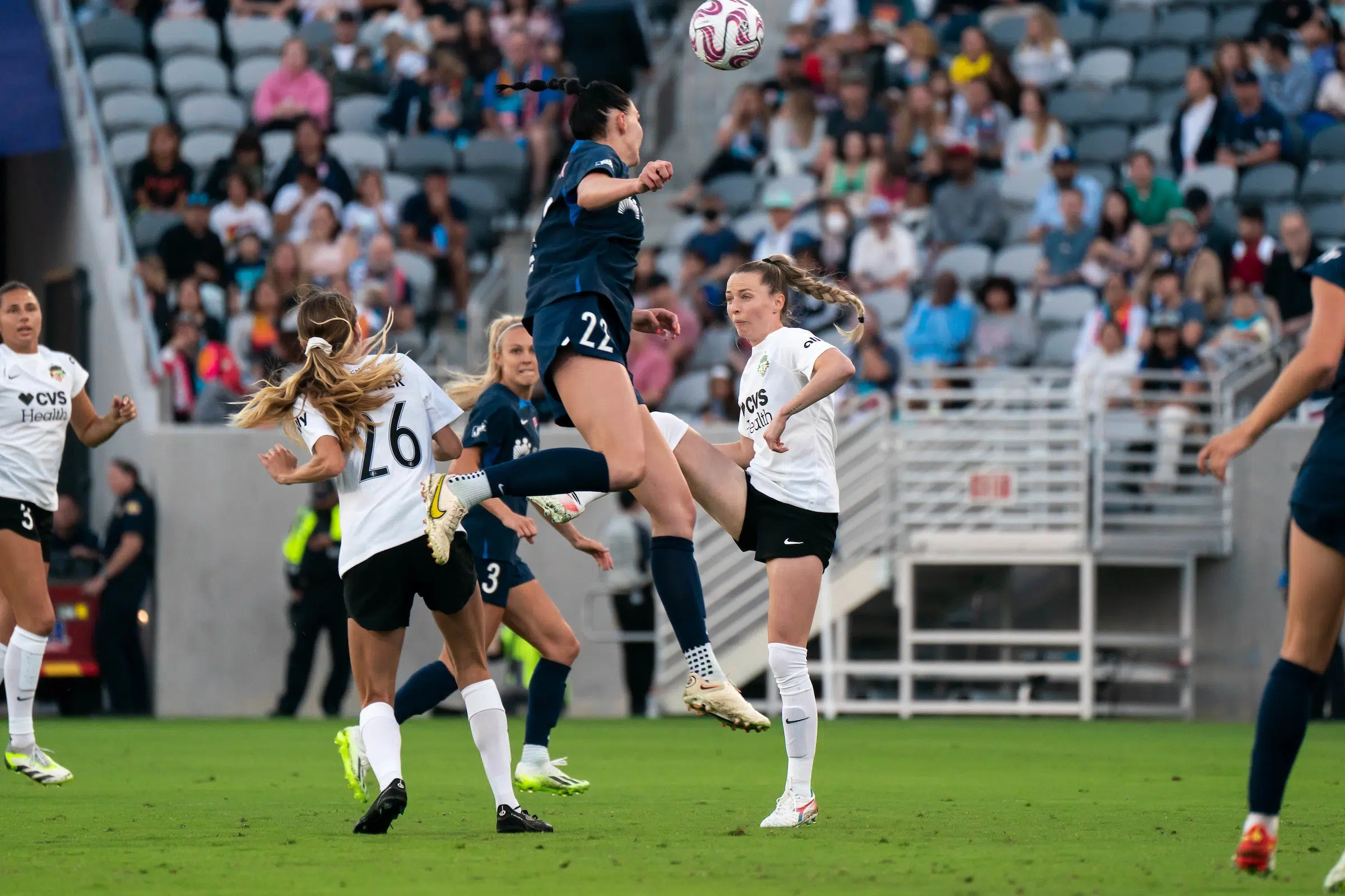 Four soccer players battle for a header.