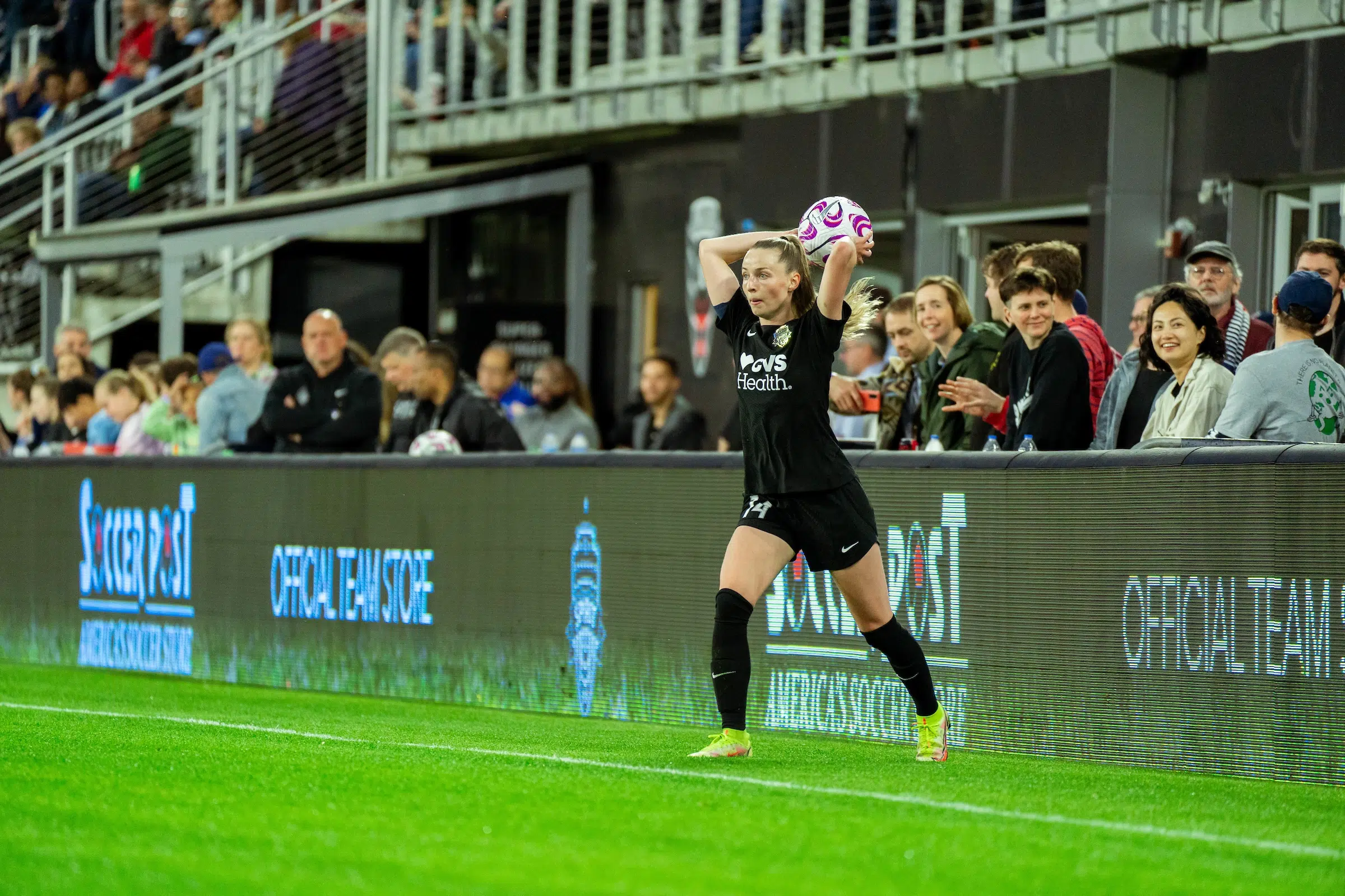 Gabby Carle in a black uniform throws a soccer ball back into the field of play.