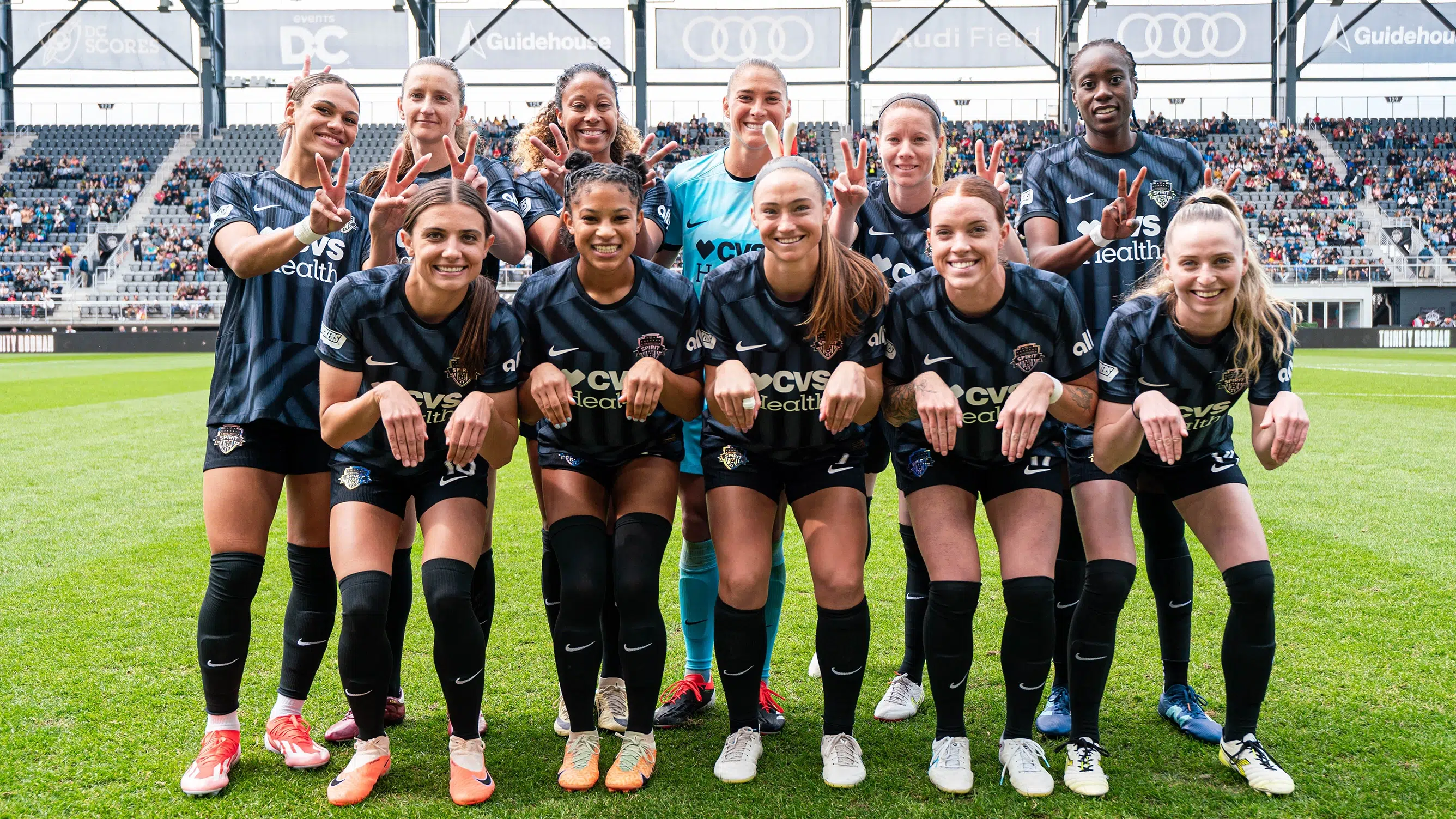 The starting eleven of the Washington Spirit pose in two rows. The first row has their hands posed like paws, and the back row puts "bunny ears" on the women in front.