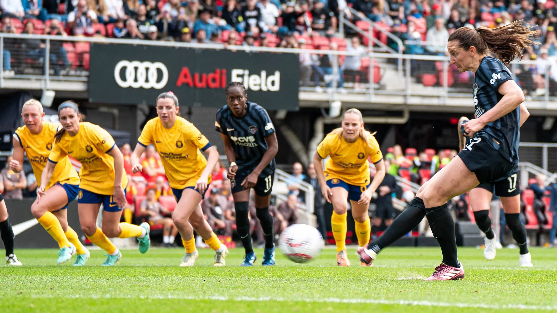 Andi Sullivan takes a penalty kick. In the background, four Utah Royals players and Ouleye Sarr are lined up and prepared to start running toward goal.