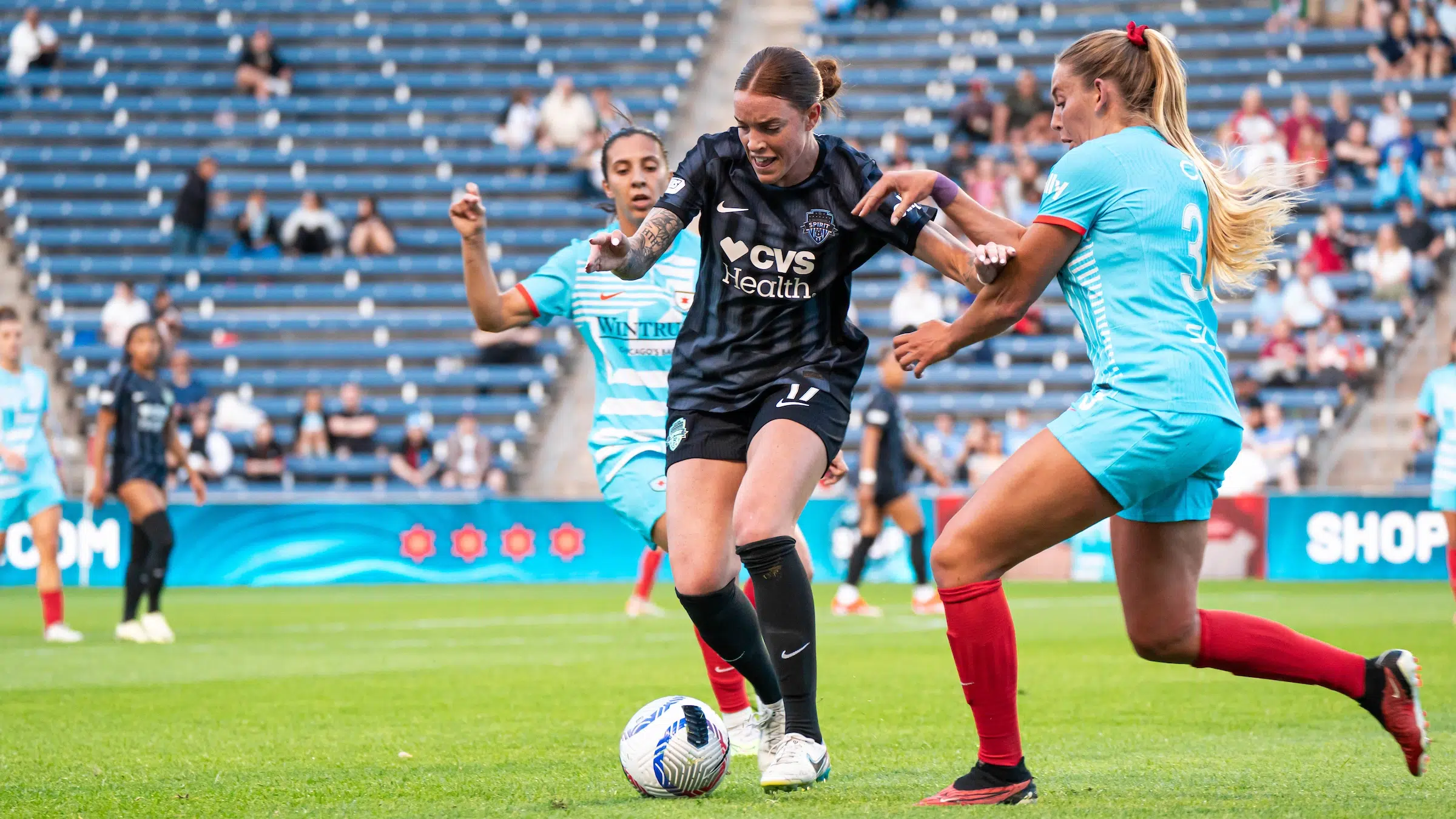 Hal Hershfelt in a black Spirit kit dribbles the ball between two Red Stars defenders.