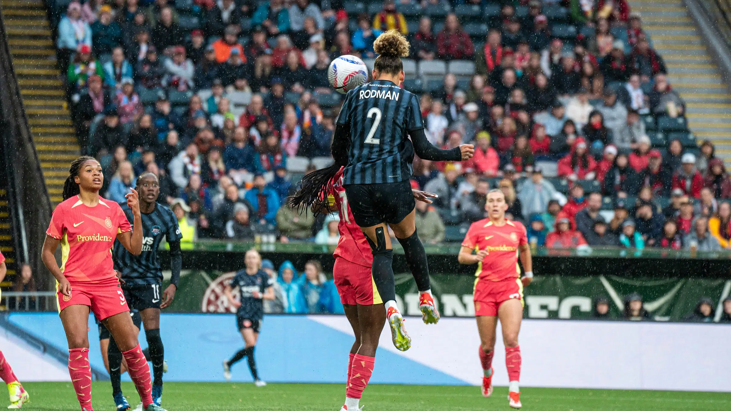 Trinity Rodman leaps in the air to head a ball over a Thorns defender.