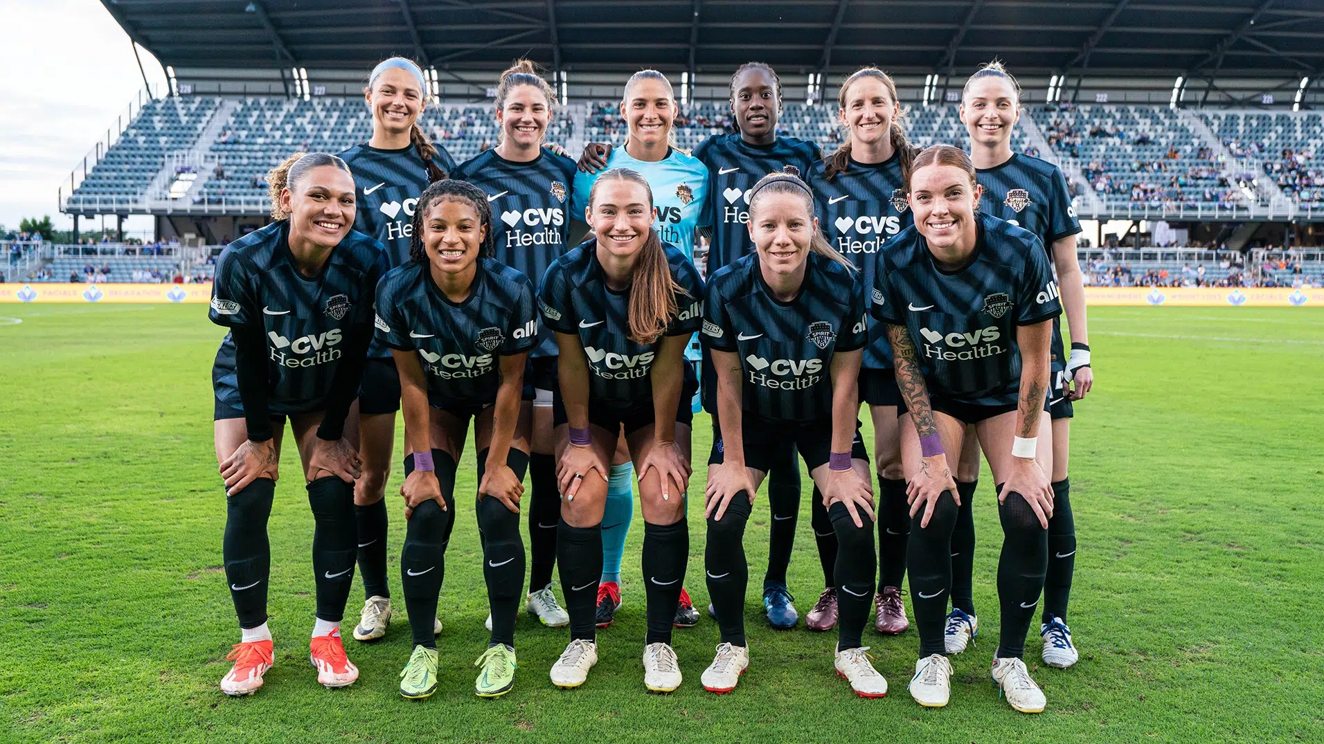 The starting eleven for the Washington Spirit pose for a photo in two rows. In the middle of the back row, Aubrey Kingsbury wears a bright blue keeper jersey.