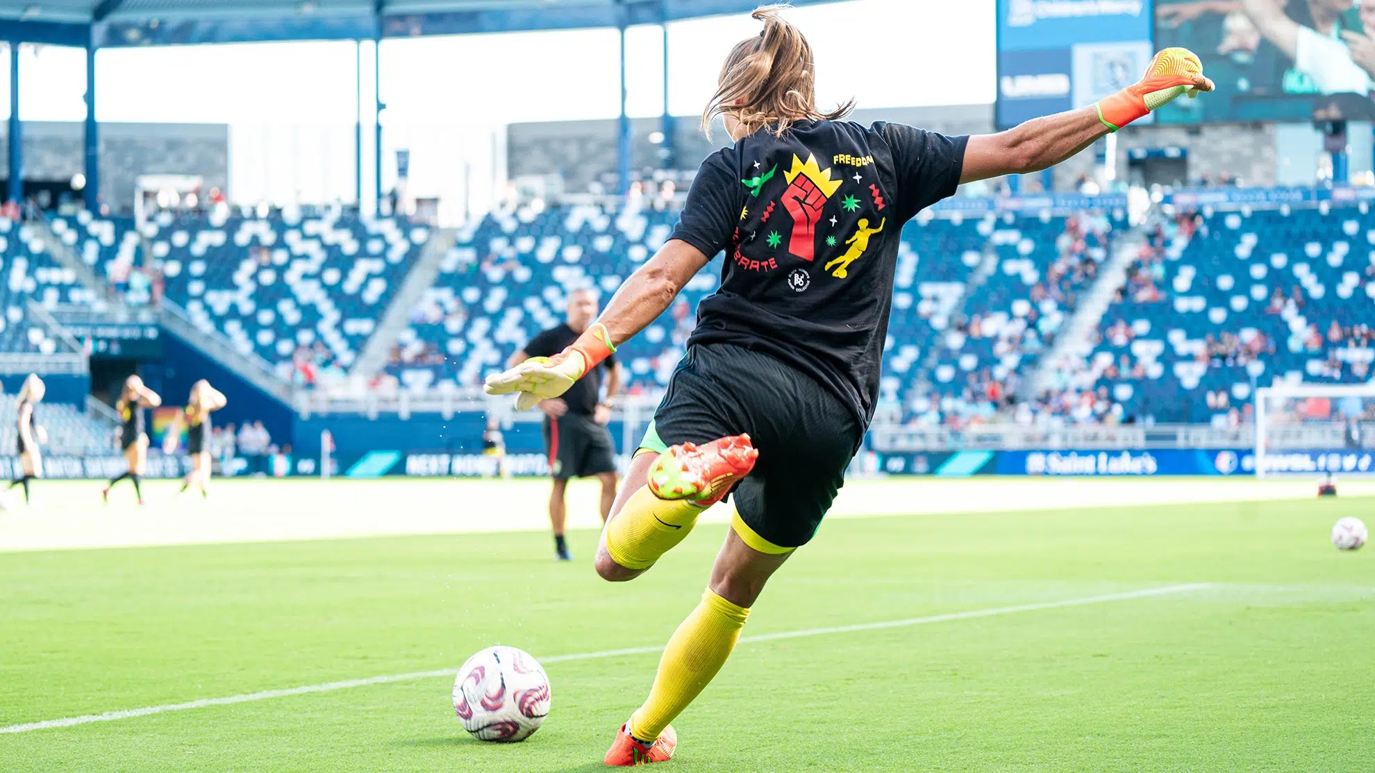 Aubrey Kingsbury winds up to kick a soccer ball while wearing a shirt from the Black Women's Player Coalition.