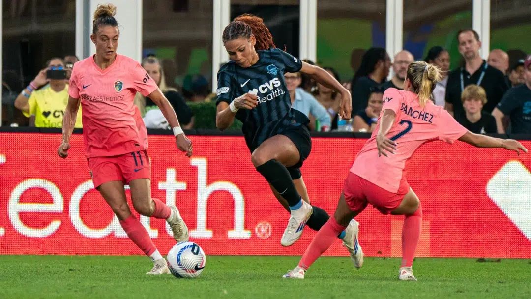 Trinity Rodman dribbles through two NC Courage defenders.