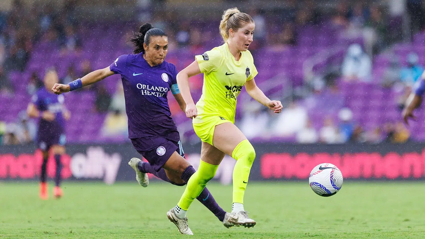 Heather Stainbrook in yellow dribbles away from Marta in purple.