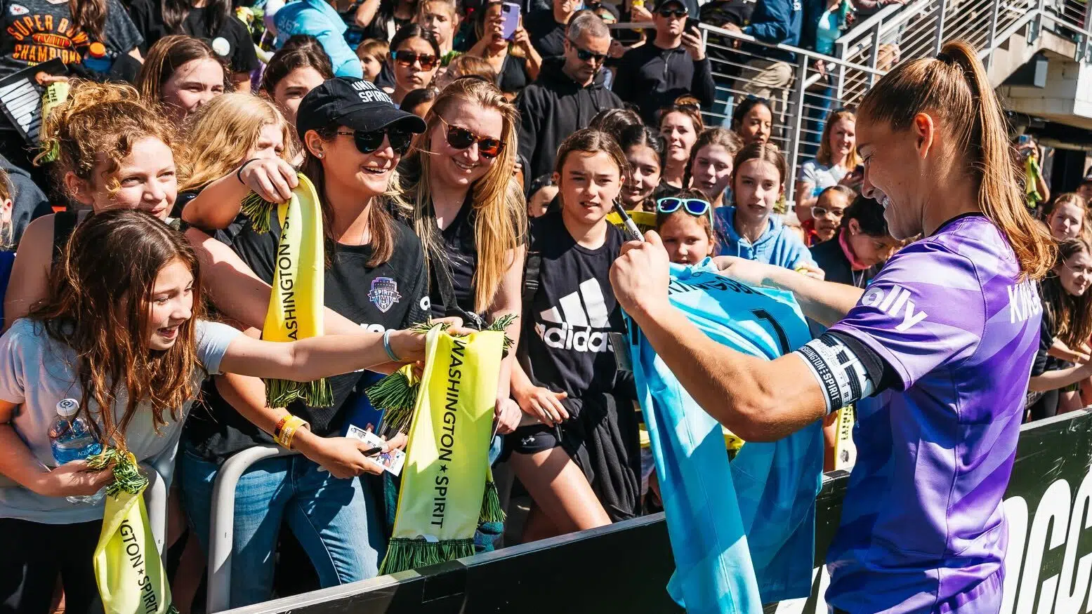Aubrey Kingsbury smiles as she autographs a blue goalkeeper jersey.