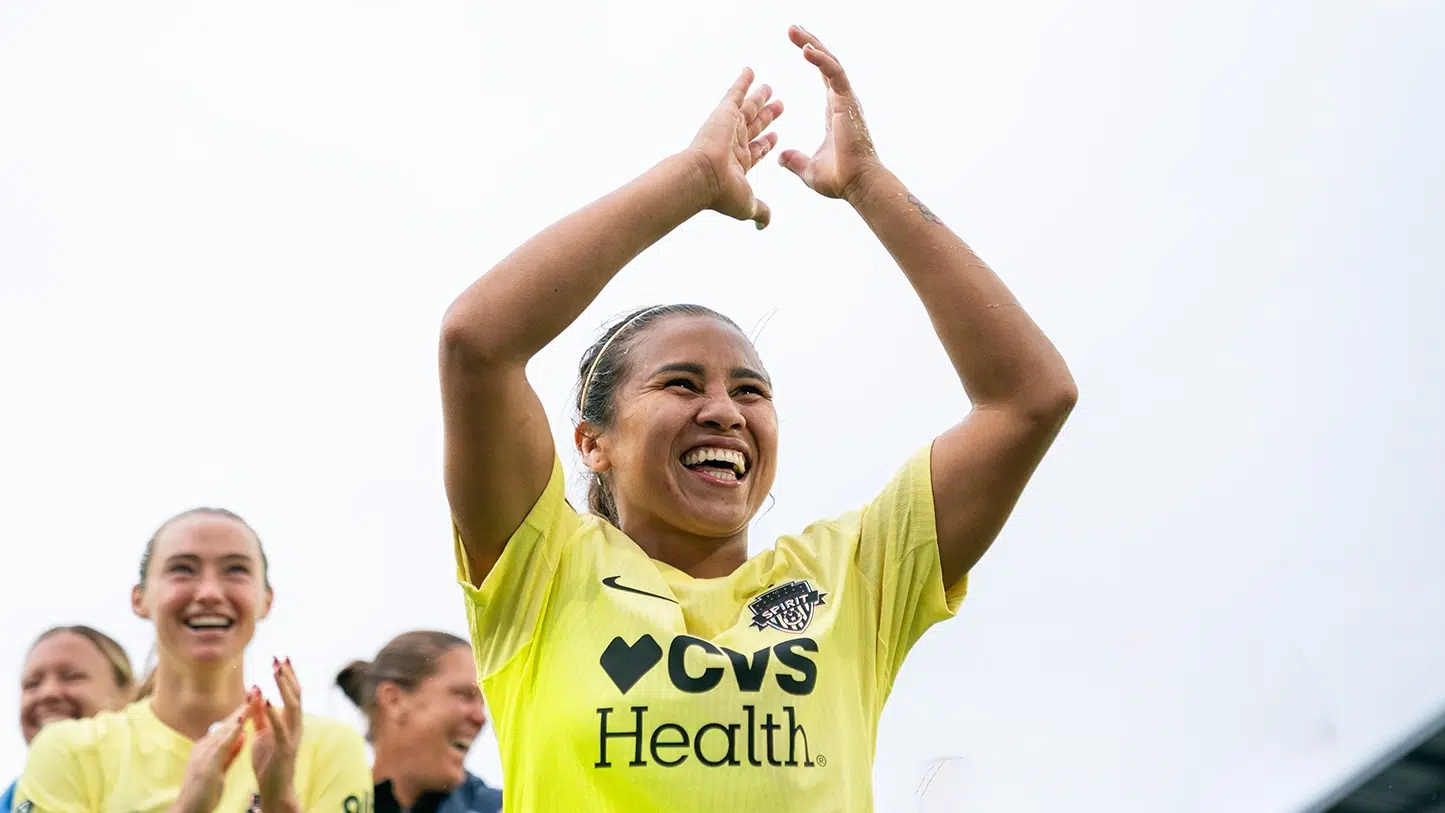 Leicy Santos raises her arms and claps at the crowd.