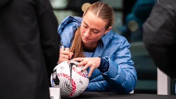 Tara McKeown autographs a soccer for a fan.