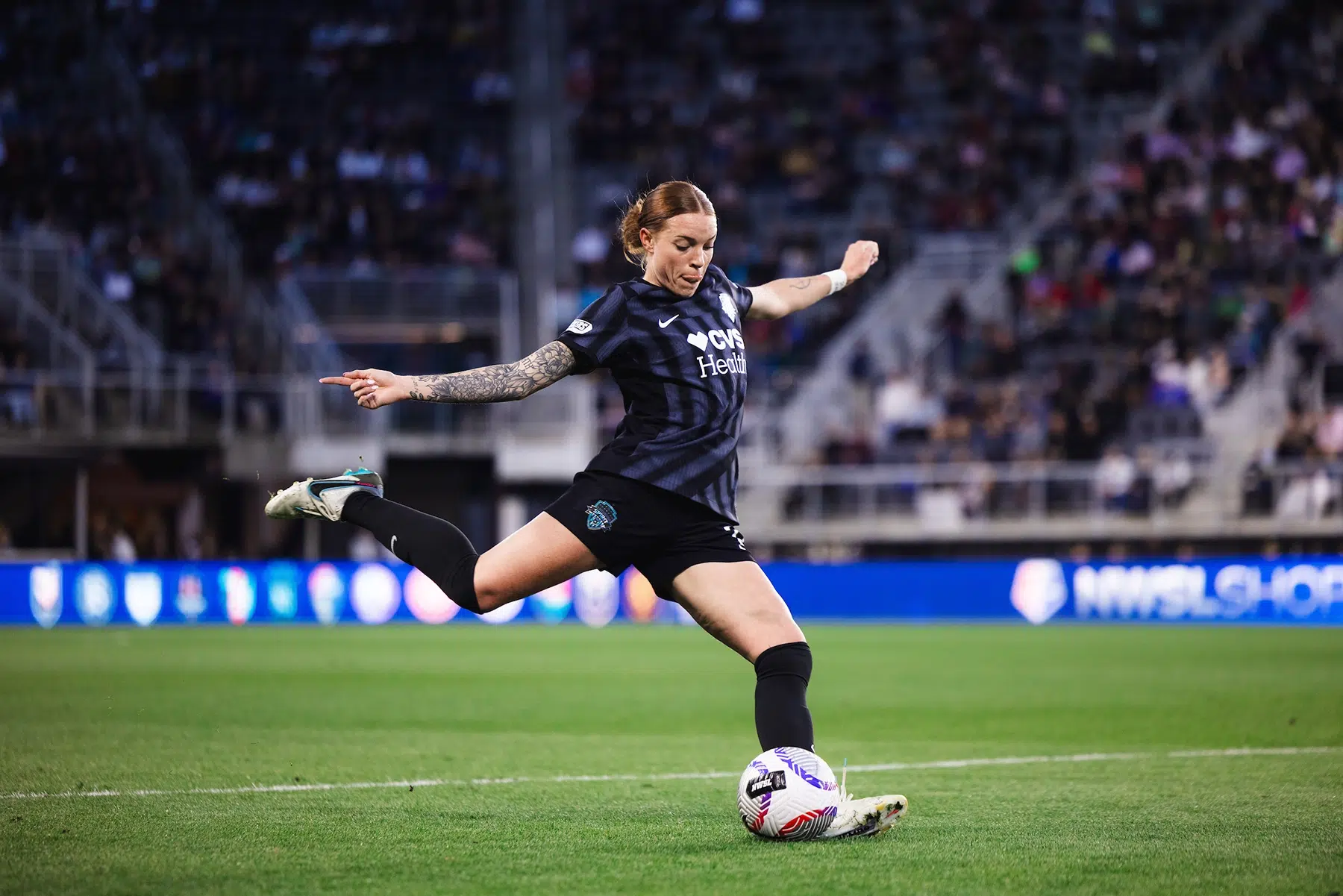 Hal Hershfelt winds up to kick a soccer ball. She is wearing a black Spirit kit with her red hair in a low bun.