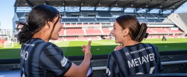 Lena Silano and Paige Metayer sit at field tables pitchside at Audi Field.