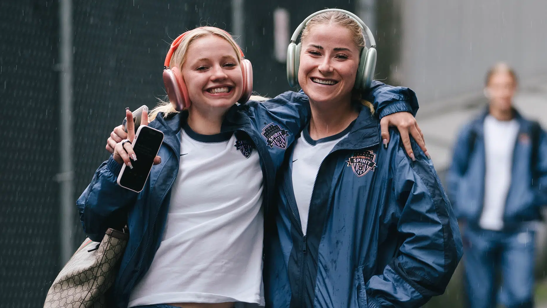 Chloe Ricketts and Heather Stainbrook in matching steel blue sweats and Apple headphones.