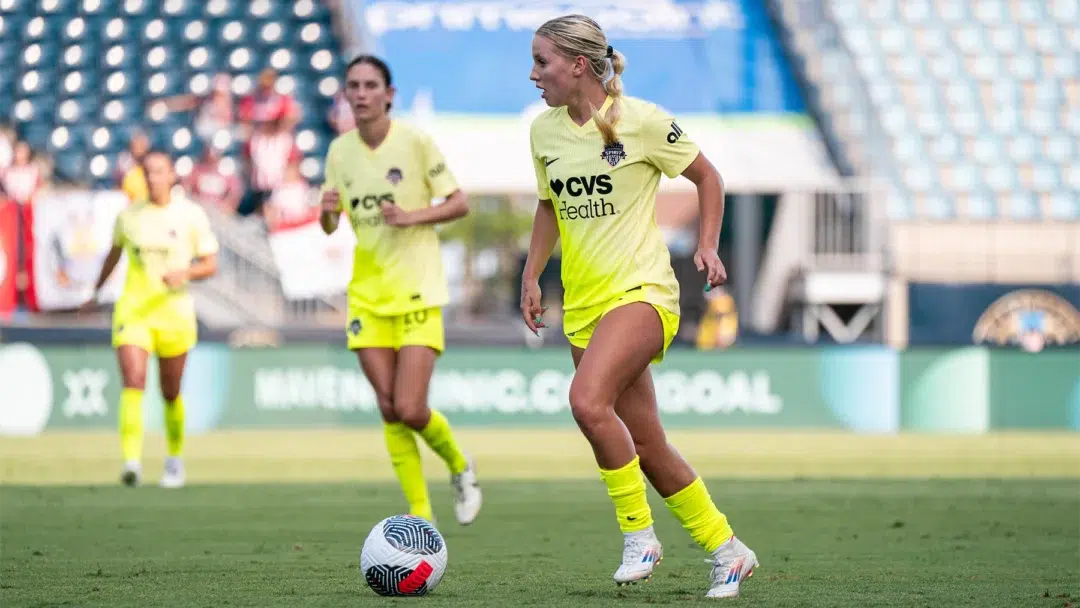 Chloe Ricketts in a yellow Spirit kit dribbles a soccer ball.