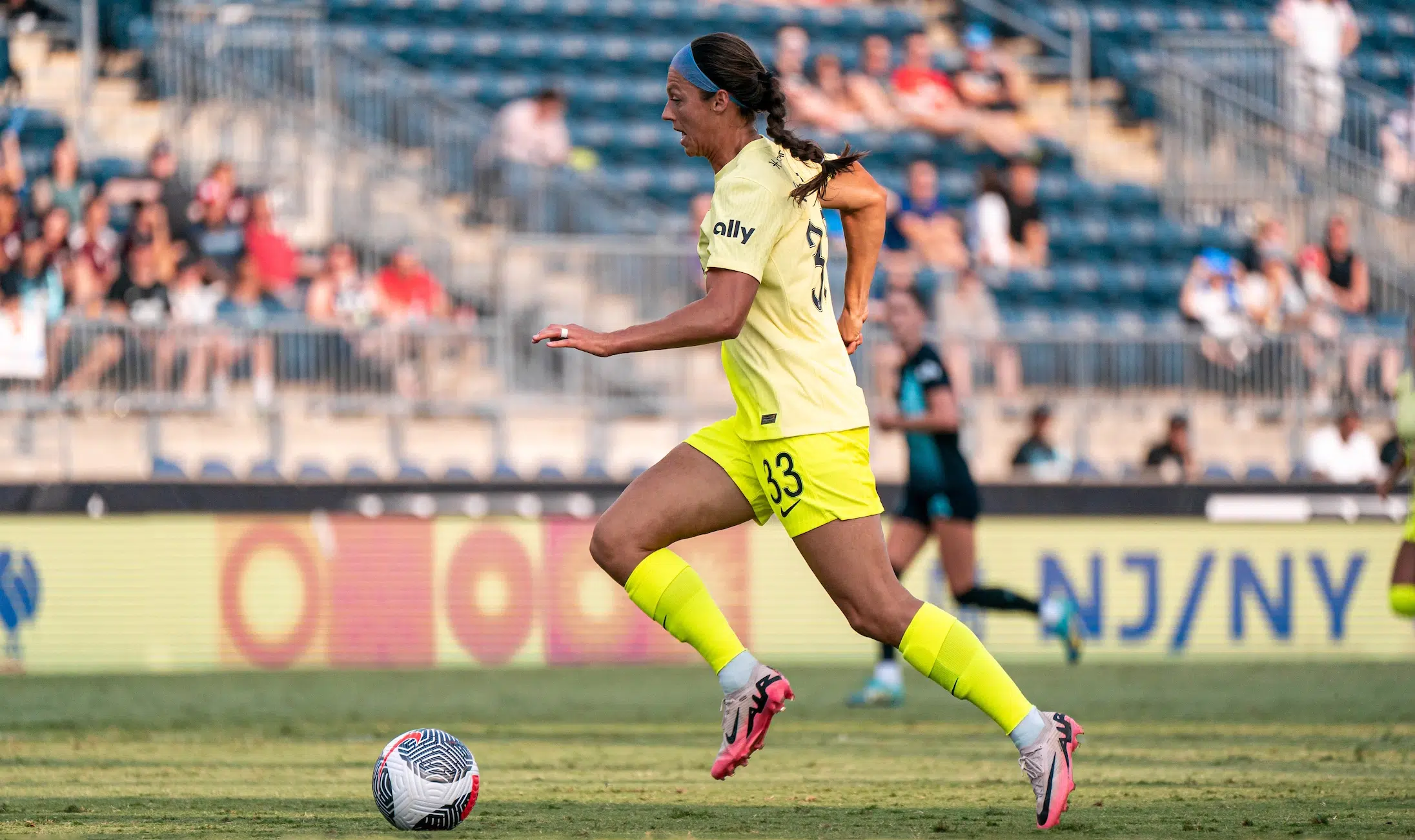 Ashley Hatch dribbles with the ball while wearing a yellow Spirit kit.