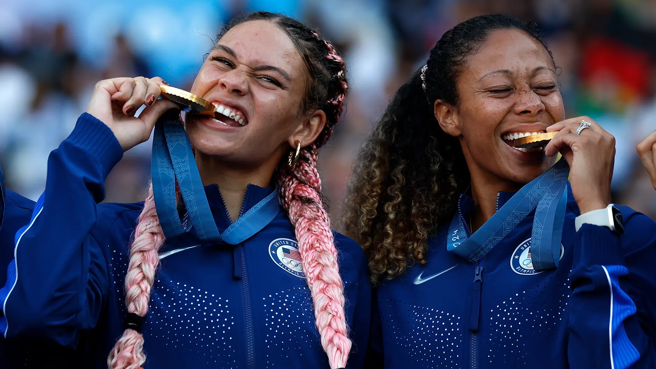 Trinity Rodman and Casey Krueger bite their gold medals.