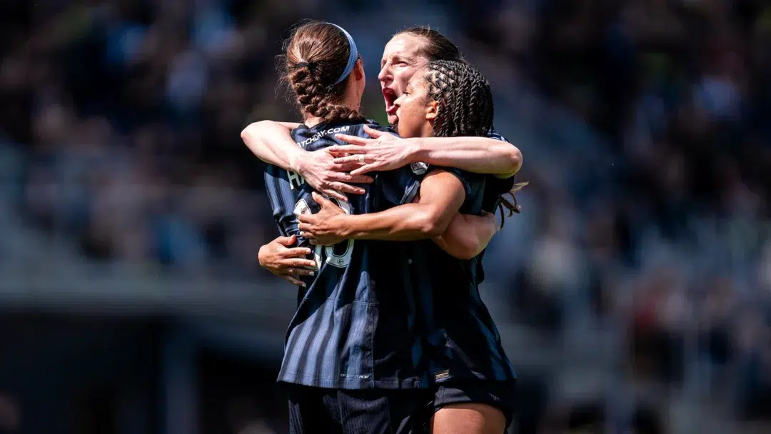 Ashley Hatch, Andi Sullivan, and Croix Bethune hug in celebration.