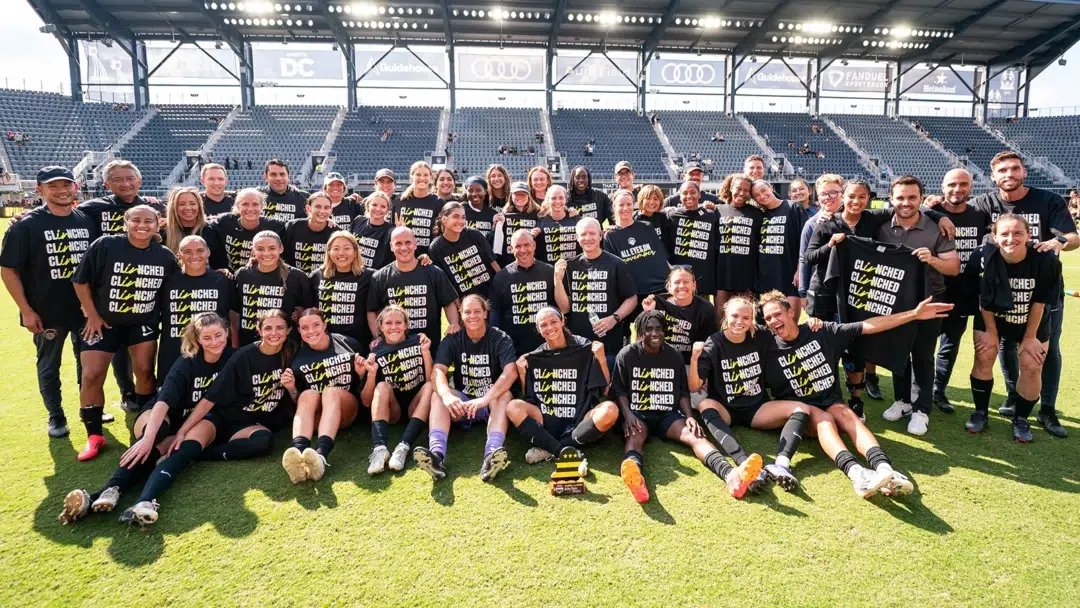 Spirit players and staff pose for a photo wearing shirts that read "CLINCHED".