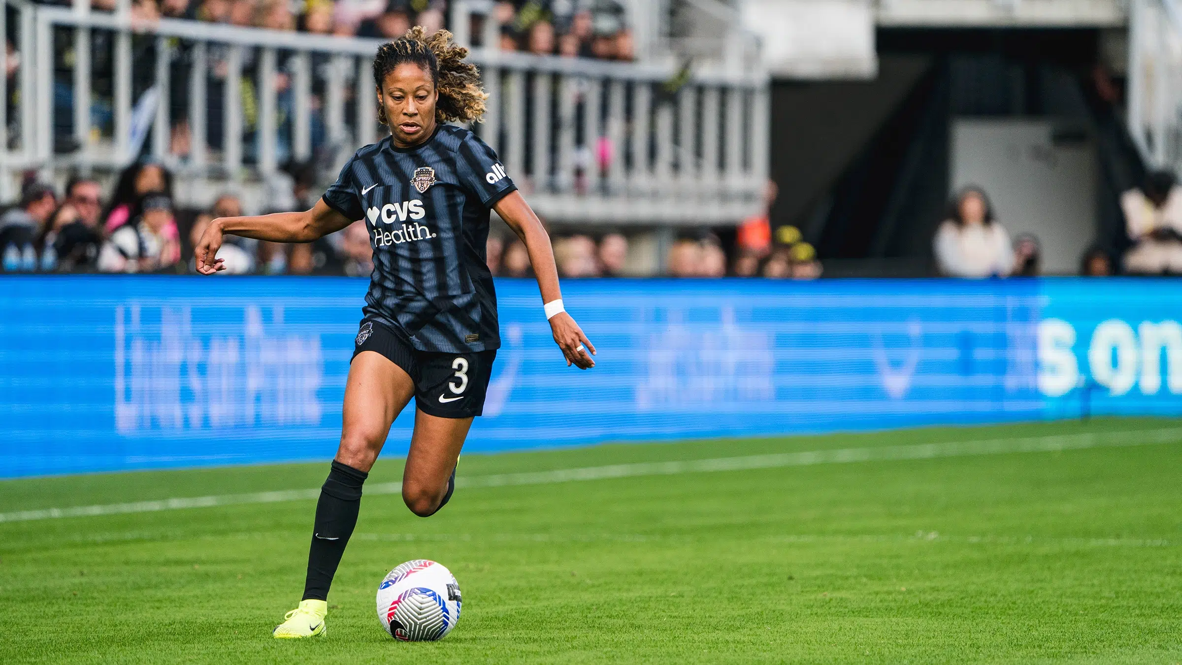 Casey Krueger in a black Spirit kit dribbles the ball.