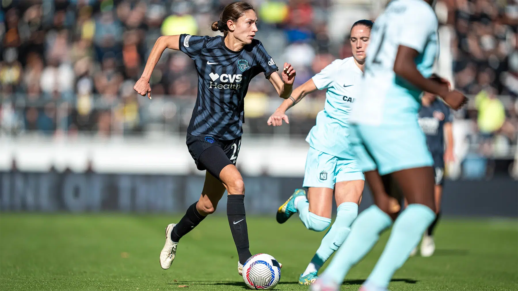 Paige Metayer in a black Spirit uniform dirbbles the ball.