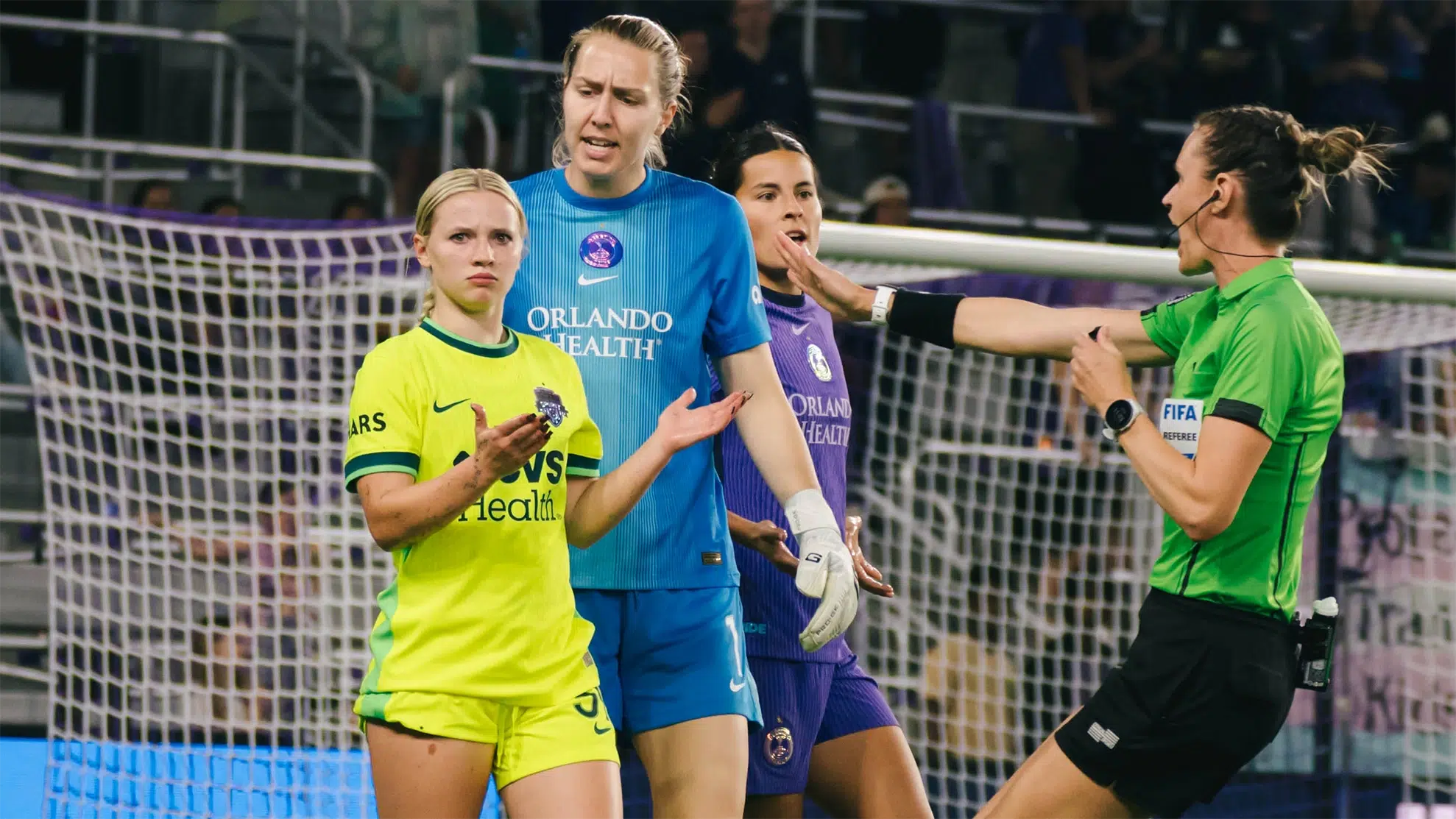 Chloe Ricketts looks unbothered while two Orlando Pride players behind her argue with the ref.