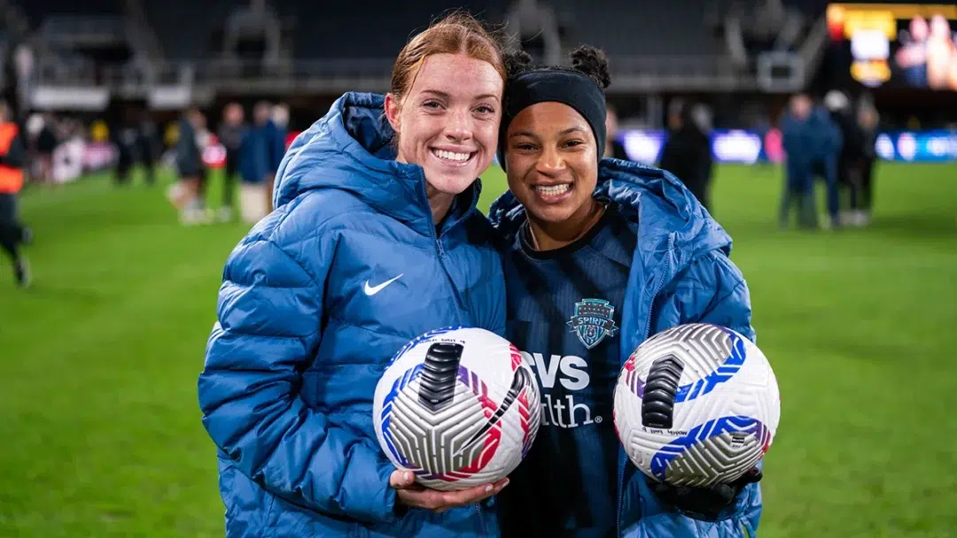 Hal Hershfelt and Croix Bethune each hold a soccer ball.