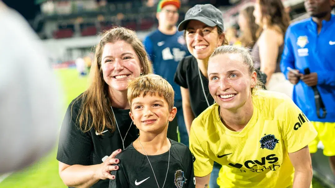 Fans take a photo with Gabby Carle in a yellow uniform.