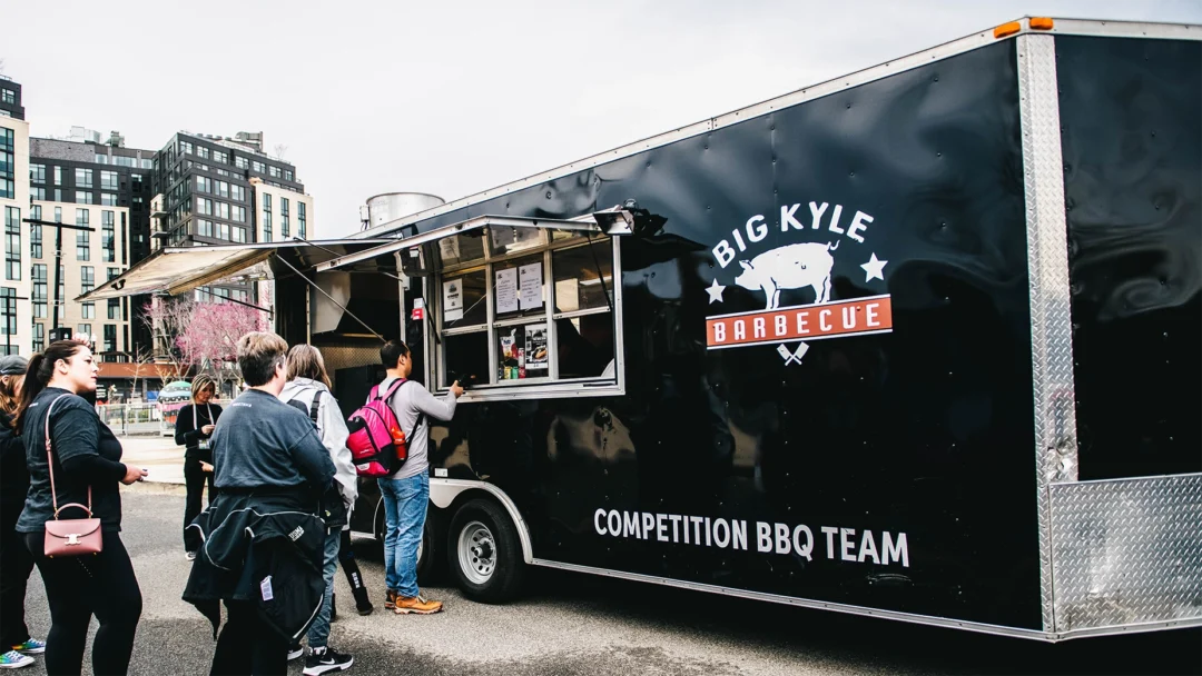 Customers in line a a black food truck.
